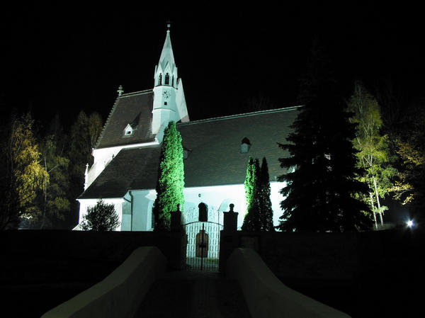 Nacht Aufnahme von der Nikolaus Kirche
Das Photo zeigt die Nikolauskirche und eine geschwungene Brücke über den Loisbach, die zu der die Kirche umfangenden Mauer mit dem schmiedeeisenen Tor führt.