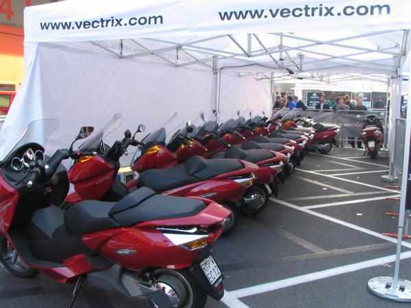 Massen an Elektromotorräder auf der EICMA
20 Vectrix elektrische Maxi Scooter bei der Teststrecke. 11 davon sind auf den Foto zu sehen. Möge es in unseren Abgas- und lärmgepeinigten Städten bald auch so aussehen.